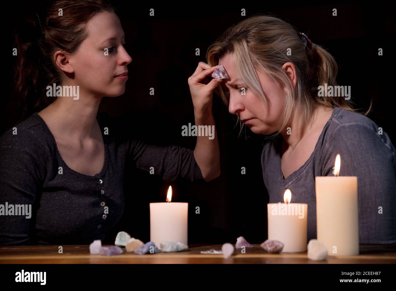 Frau hält einen Heilstein auf dem Kopf, prophezeien und telepathische Therapie, esoterische Hilfe Stockfoto