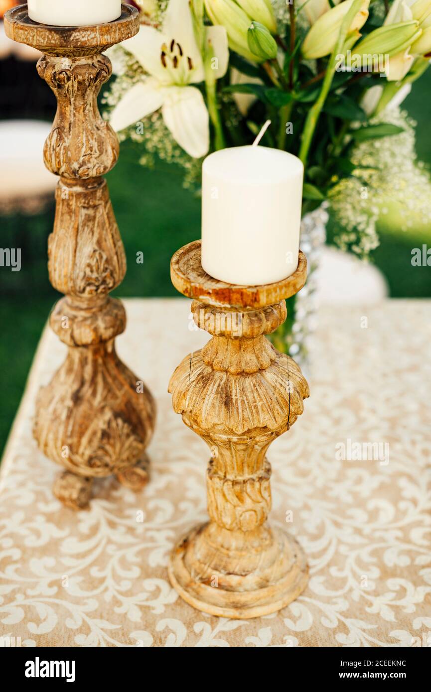Weiße Kerze auf Vintage Holzhalter an den Blumen platziert. Stockfoto