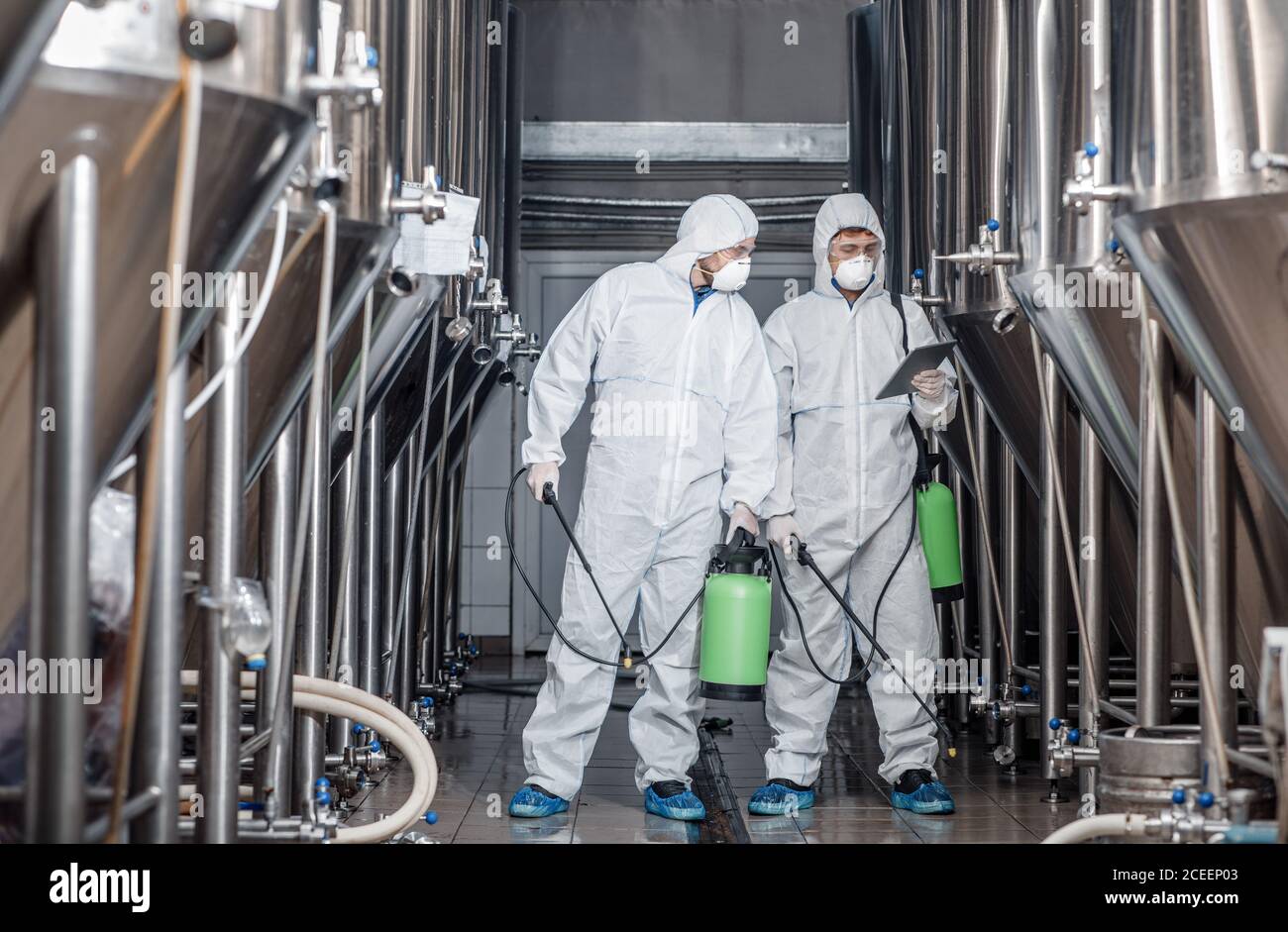 Jungs in Hazmat Anzüge und Masken desinfizieren Brauerei Wasserkocher an Handwerksbetrieb Stockfoto