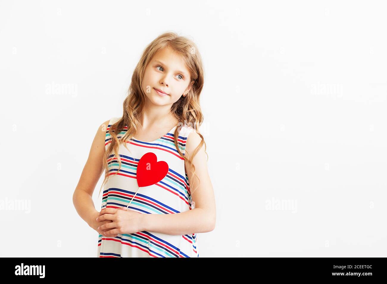 Nahaufnahme Porträt eines schönen kleinen Mädchen vor weißem Hintergrund. Schöne Teenager-Mädchen hält rote Papier Herz. Ultraschall des Herzens. Mädchen und Pubertät Co Stockfoto
