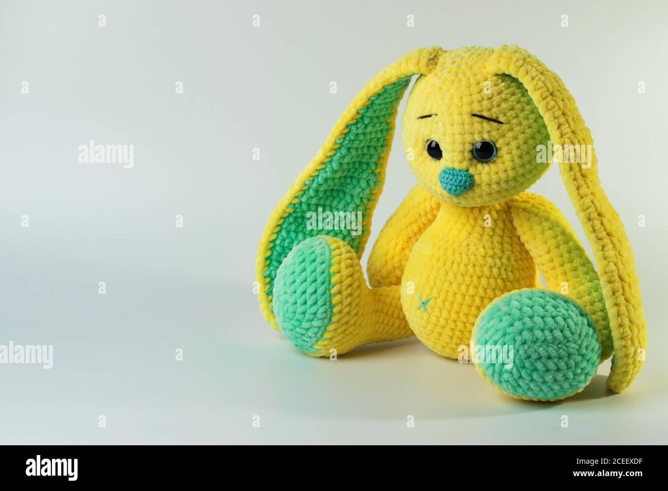 Ein weicher gelber Hase auf weißem Hintergrund mit einer Kopie des Raumes. Kinderspielzeug. Es ist Platz für Text Stockfoto