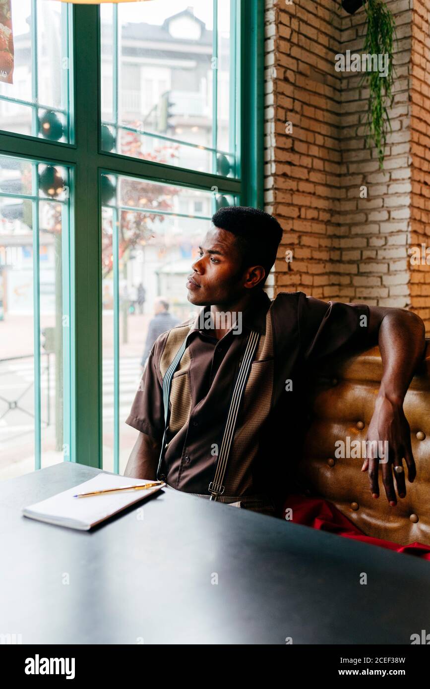 Serious african männlich in roter Jacke Brief am Tisch in Café Stockfoto
