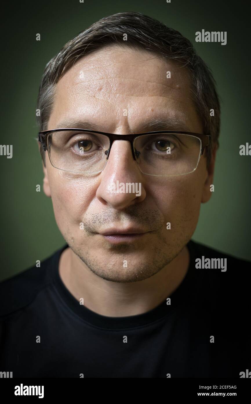 Porträt eines ernsten 40-jährigen weißen (kaukasischen) Mannes mit Brille. Rembrant Beleuchtung. Stockfoto