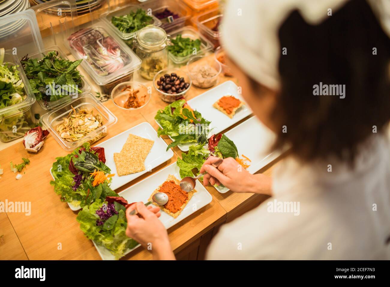 Rückansicht einer unkenntlichen Frau, die Gerichte mit Kräutern und Snacks serviert. Stockfoto