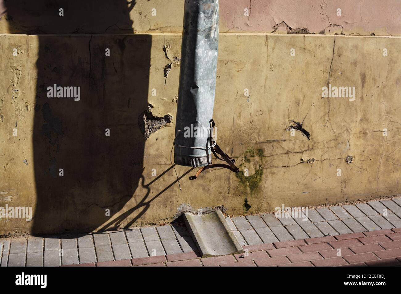 Zinn Drainpipe gegen Grunge schäbig schimmelige Wand bei Kontrast Sonnenlicht, Wasserleck, Utility Streit Stockfoto