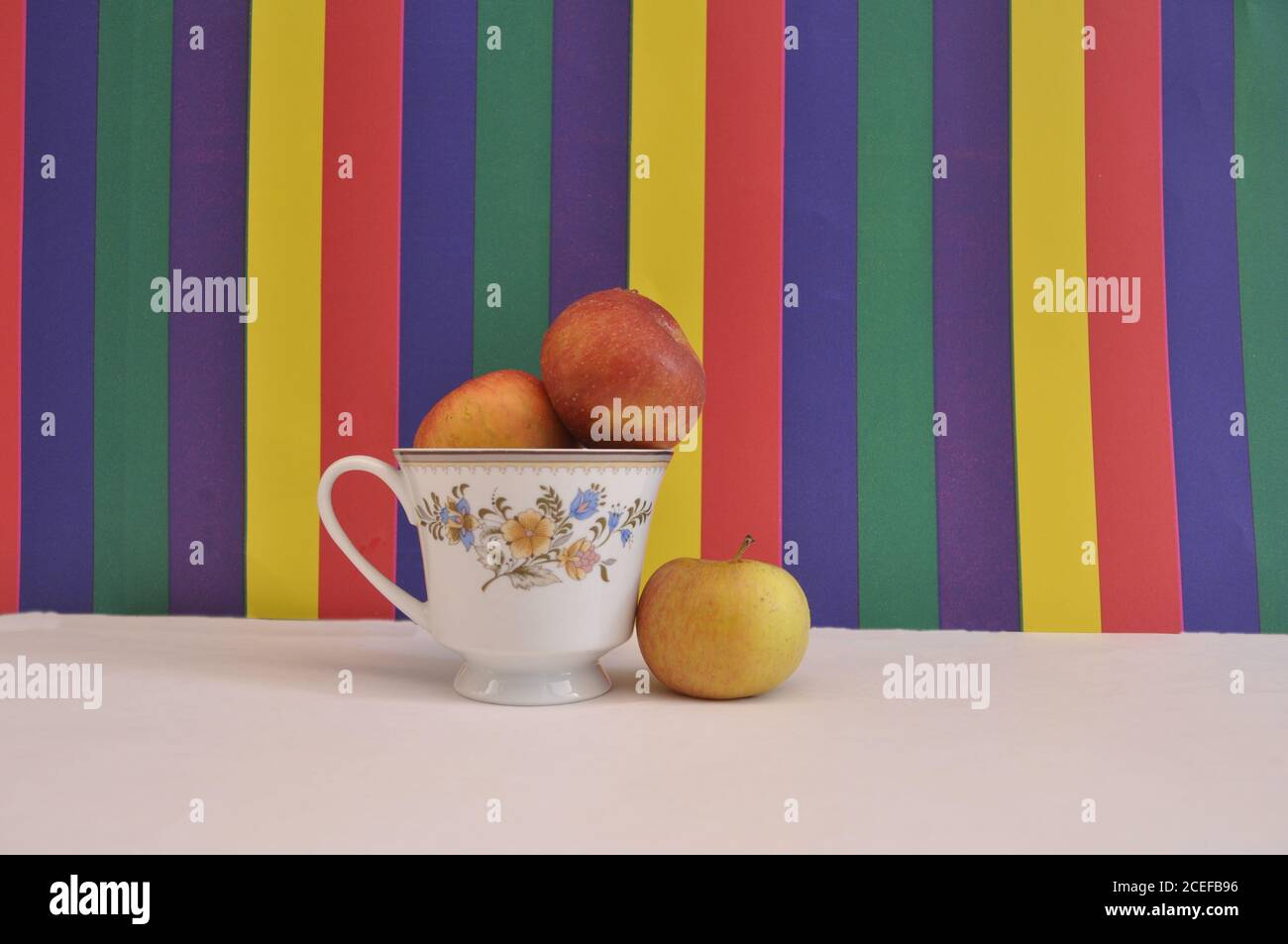 Äpfel in einer Blumentasse mit einem isolierten Apfel geben Das Konzept der Trennung auf farbigem Hintergrund und weißer Basis Stockfoto