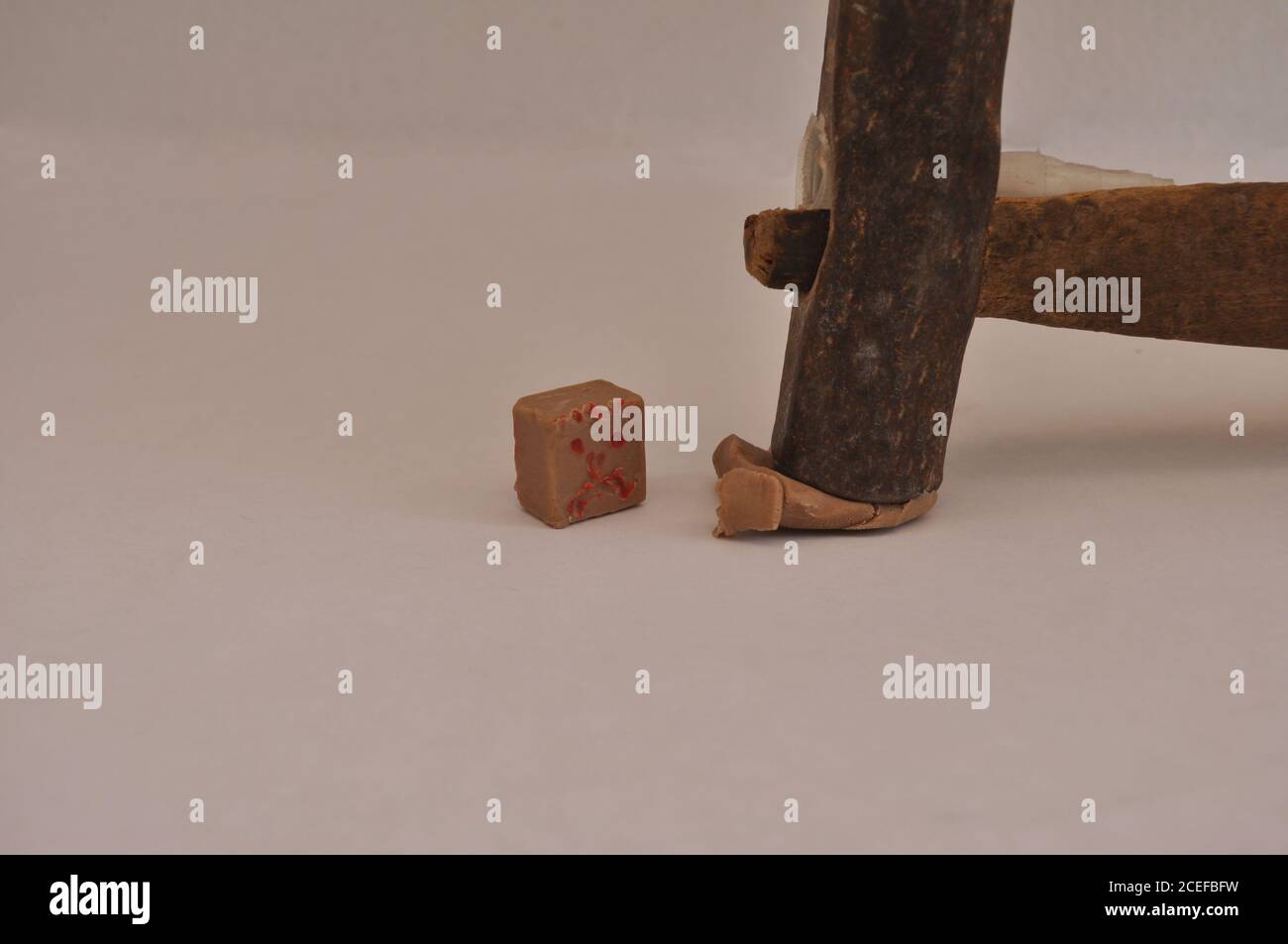 Eisenhammer mit Holzgriff, zerstören eine Süßigkeiten in Form eines Würfels, in konzeptionellen Foto, weißer Hintergrund, Brasilien, Südamerika Stockfoto