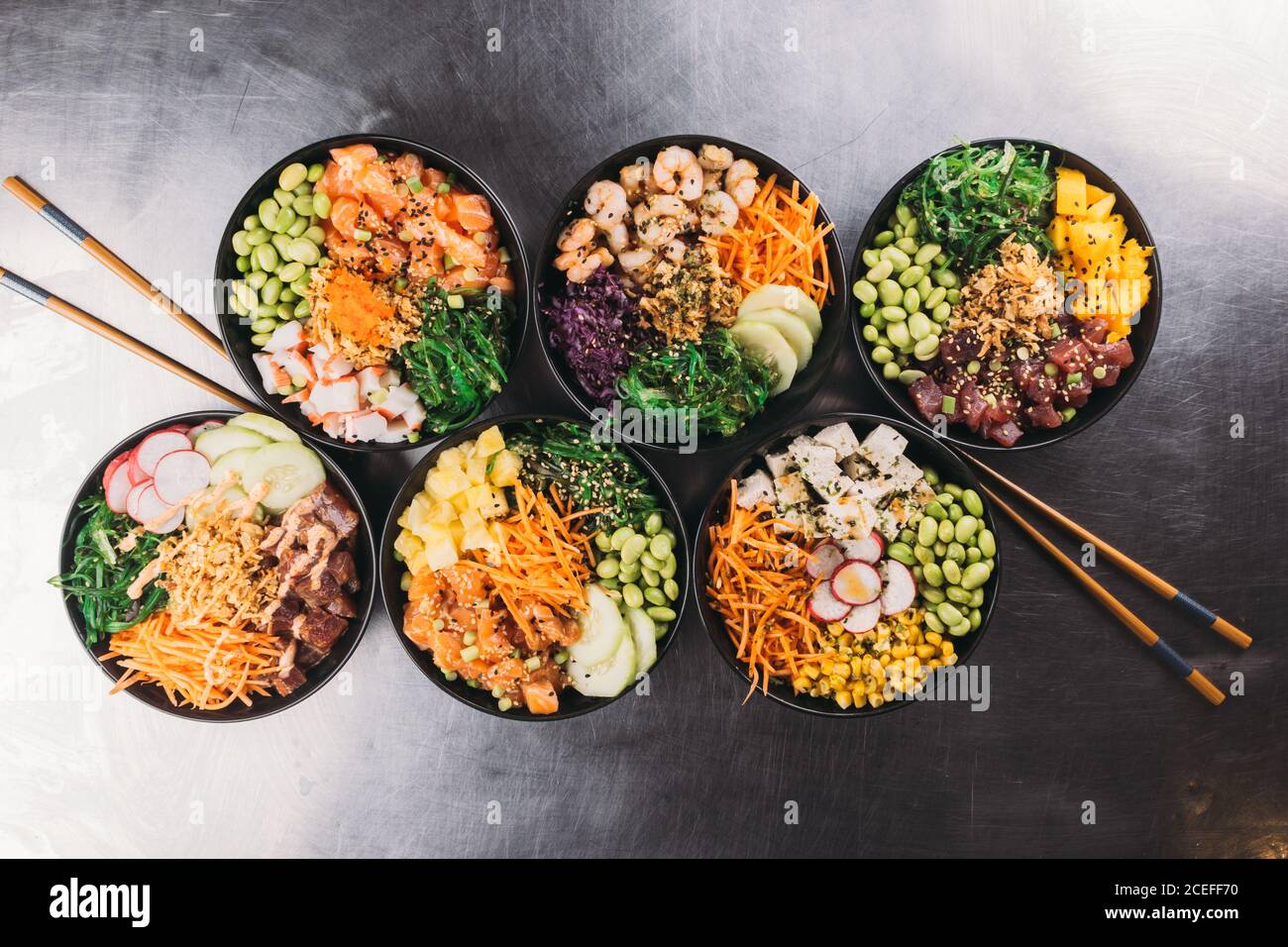 Keramikschalen mit verschiedenen Gerichten der asiatischen Küche stehen auf Schwarzer Holzhintergrund Stockfoto