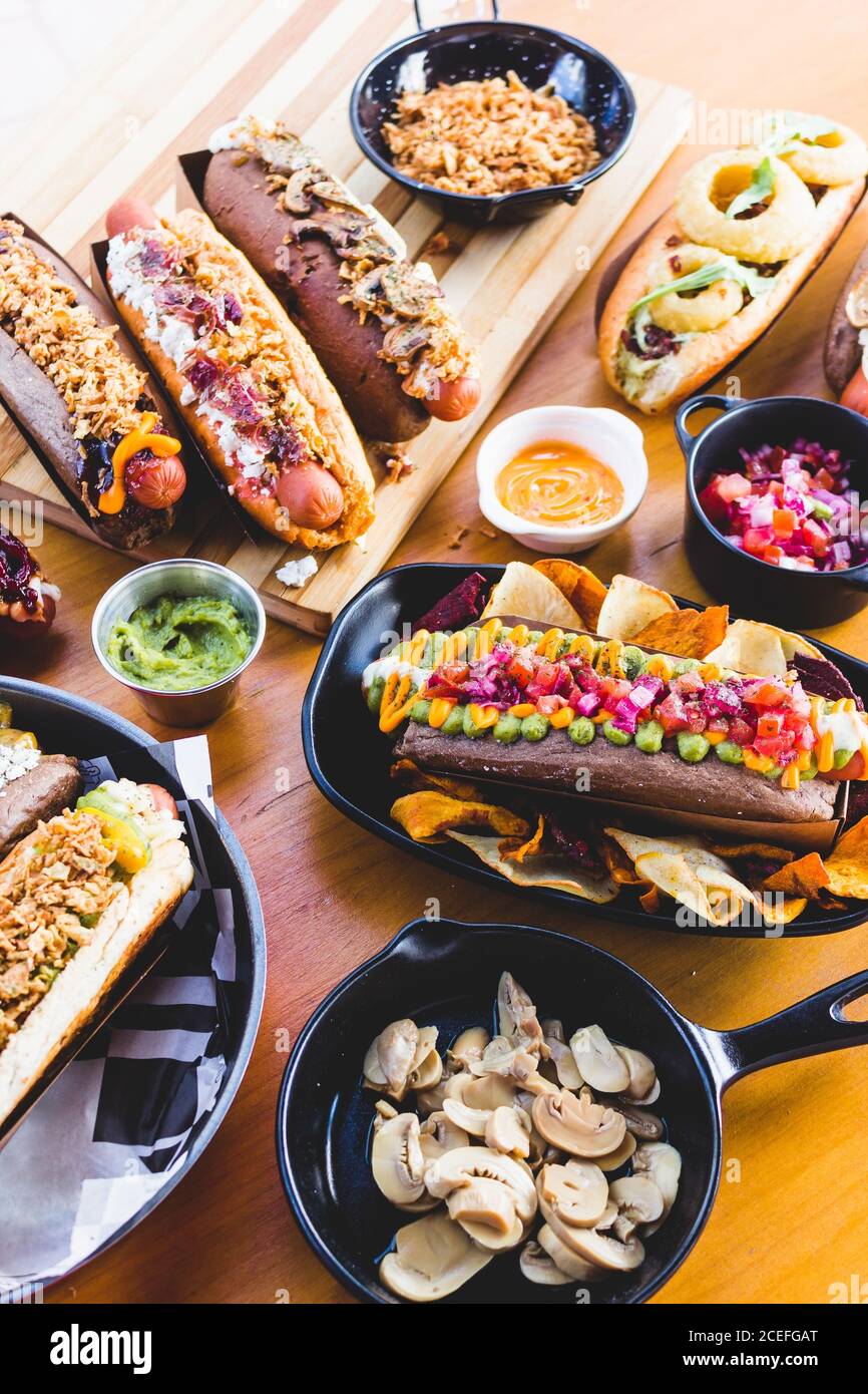 Flache Lay von großer Menge an leckeren Speisen von Hot Dogs und Snacks auf Holztisch serviert. Stockfoto