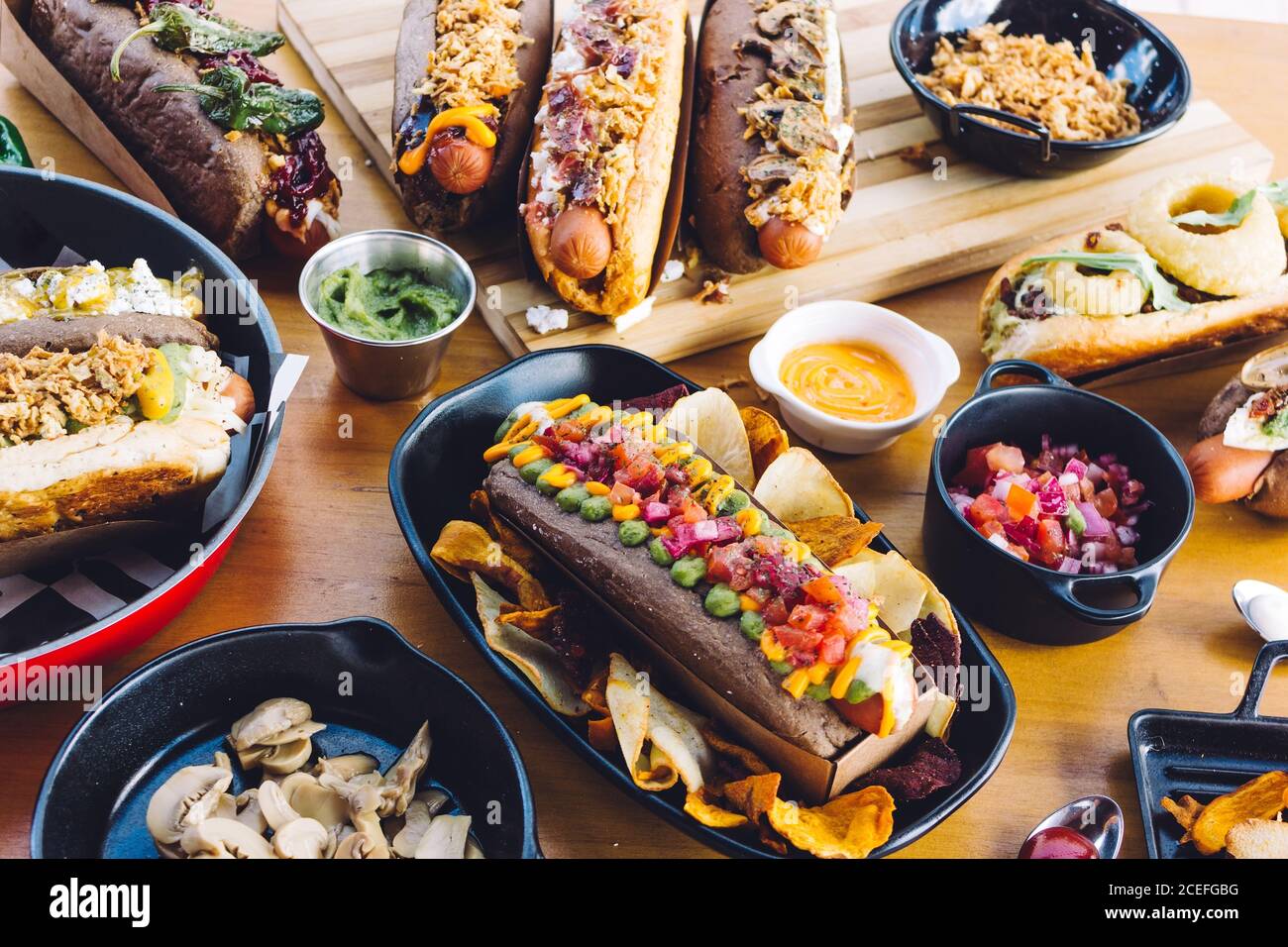 Flache Lay von großer Menge an leckeren Speisen von Hot Dogs und Snacks auf Holztisch serviert. Stockfoto