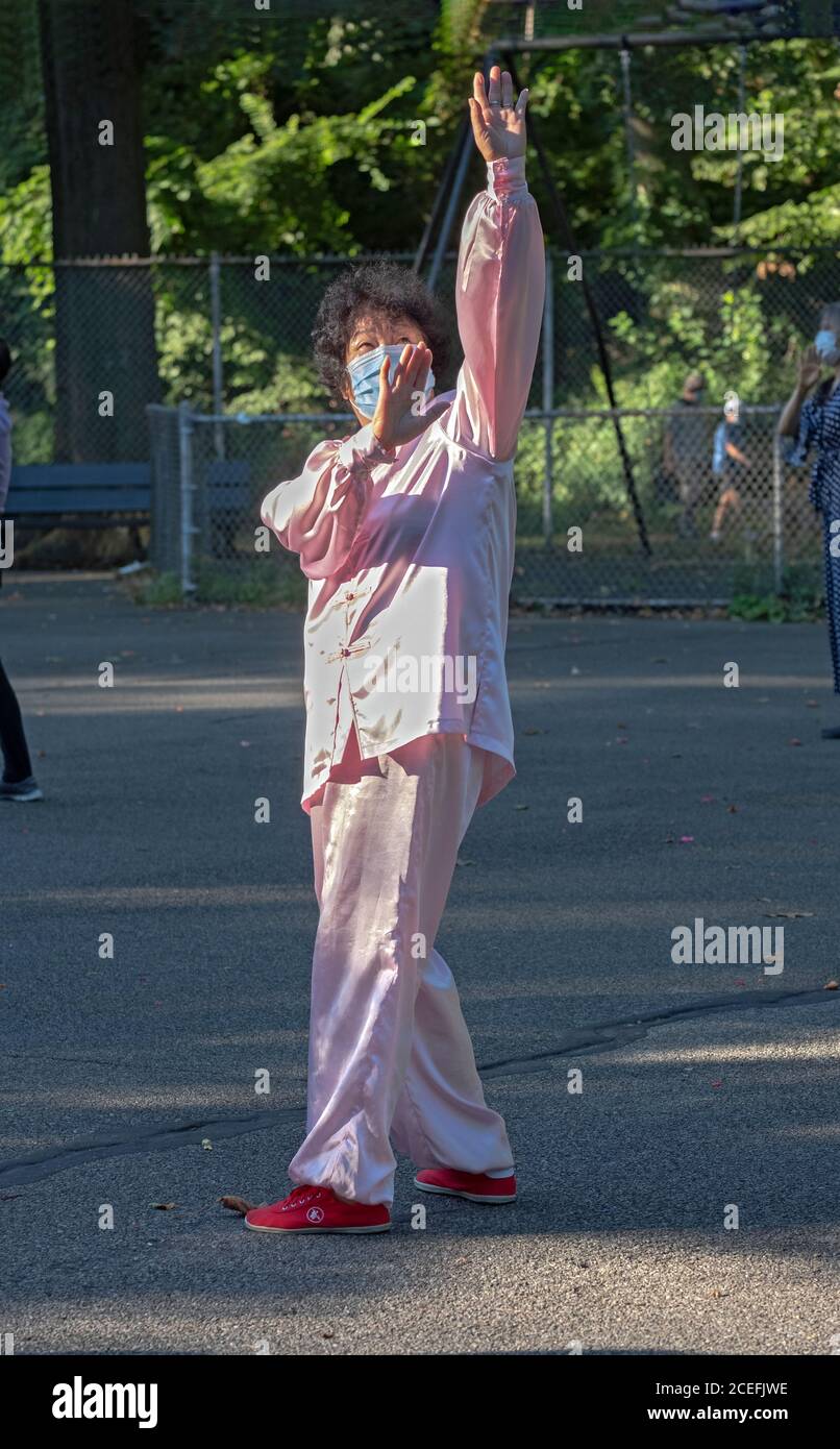 Eine ältere chinesisch-amerikanische Frau, die einen traditionellen tang-Anzug, rote Schuhe und eine chirurgische Maske bei einem Tai-Chi-Kurs in einem Park in Flushing, Queens, New York, trägt. Stockfoto