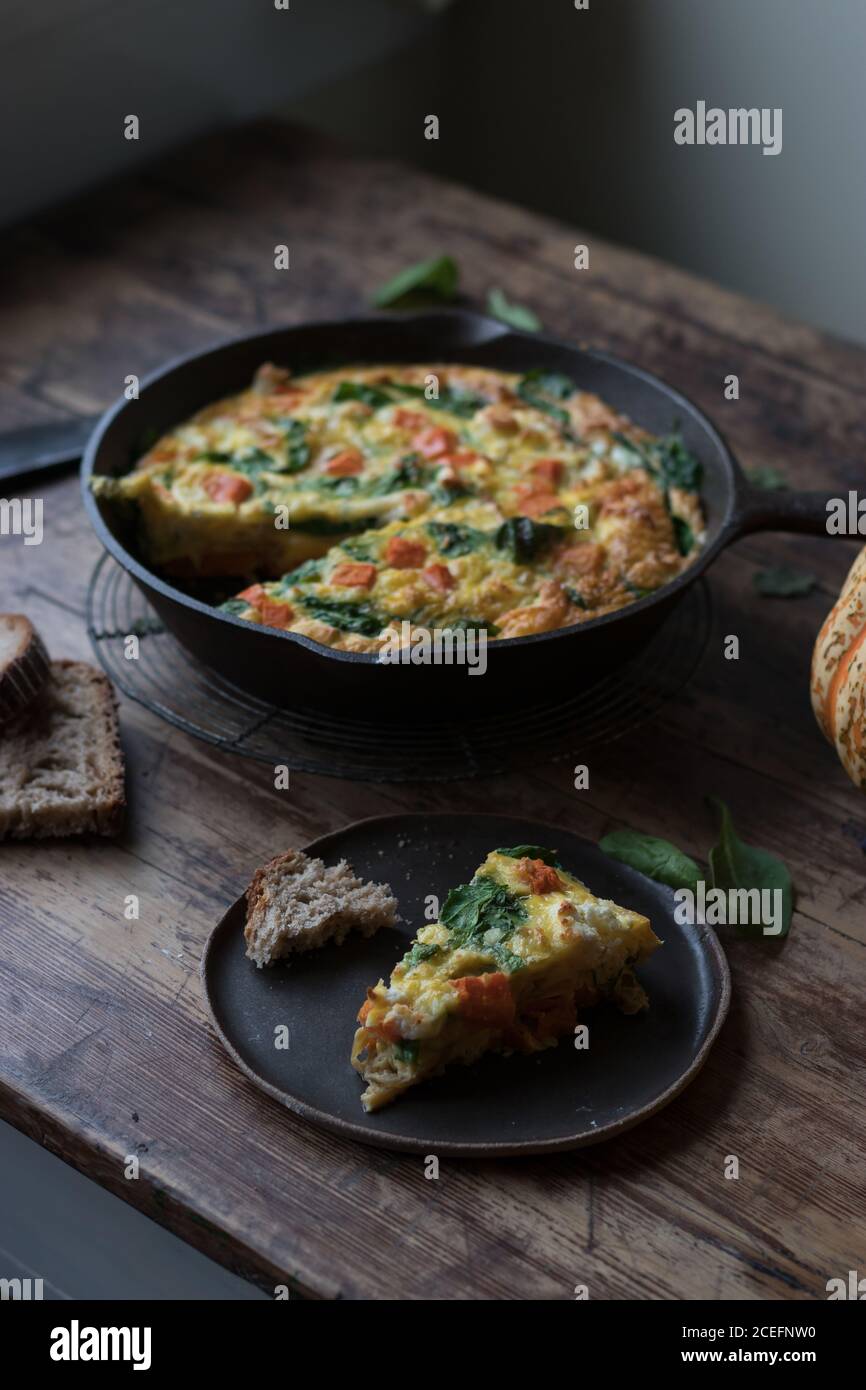 Teller und Metall-Topf mit leckeren Kürbis und Spinat frittata Auf Holztischplatte stehend Stockfoto