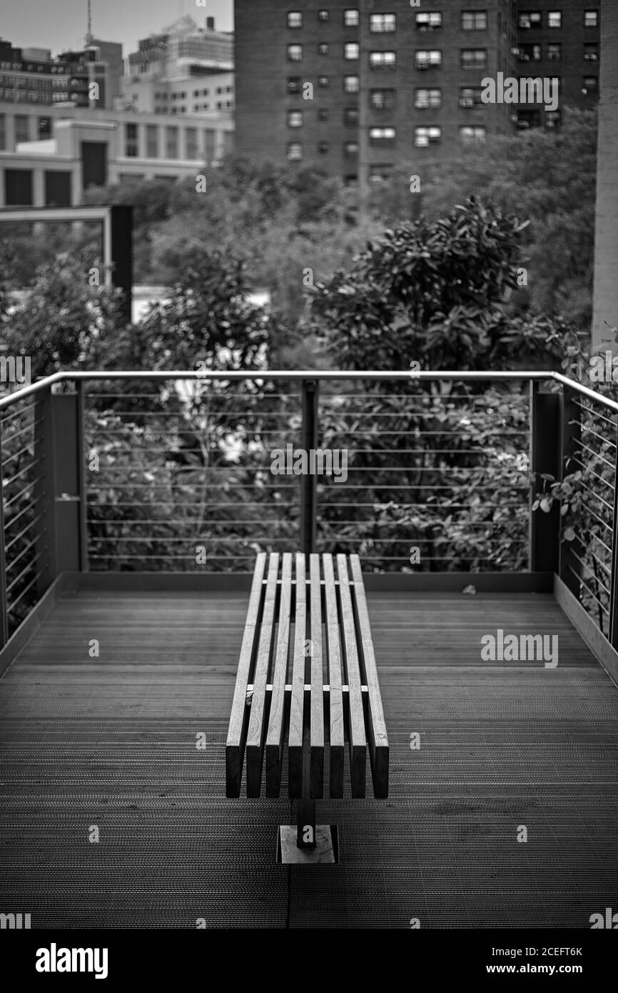 Schwarz-Weiß-Aufnahme einer kleinen Holzbank auf dem Balkon in New York City. Stockfoto