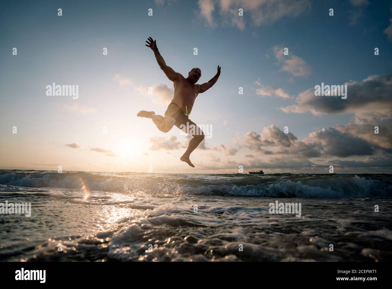 Silhouette eines Mannes, der am Strand springt. Stockfoto