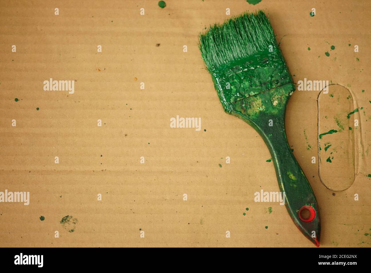Alte Bürste mit grüner Farbe auf braunem Papierbogen befleckt Stockfoto