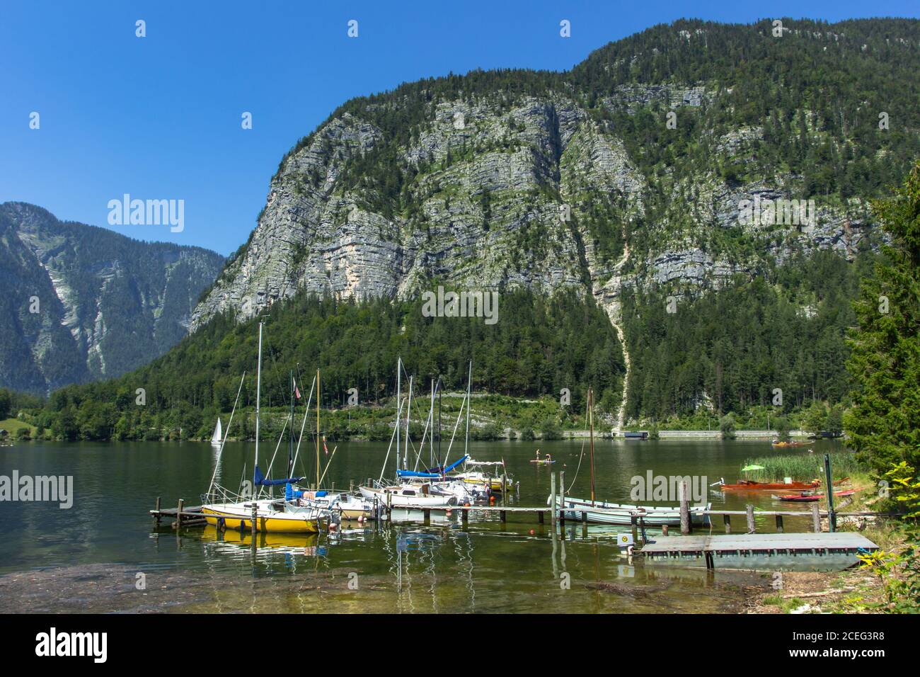 Yachten und Boote in einem kleinen Hafen an einem Alpensee, Klippen und Berge im Hintergrund. Reisen Sie durch die malerische Landschaft. Yachting an sonnigen Tag.Sommer vac Stockfoto