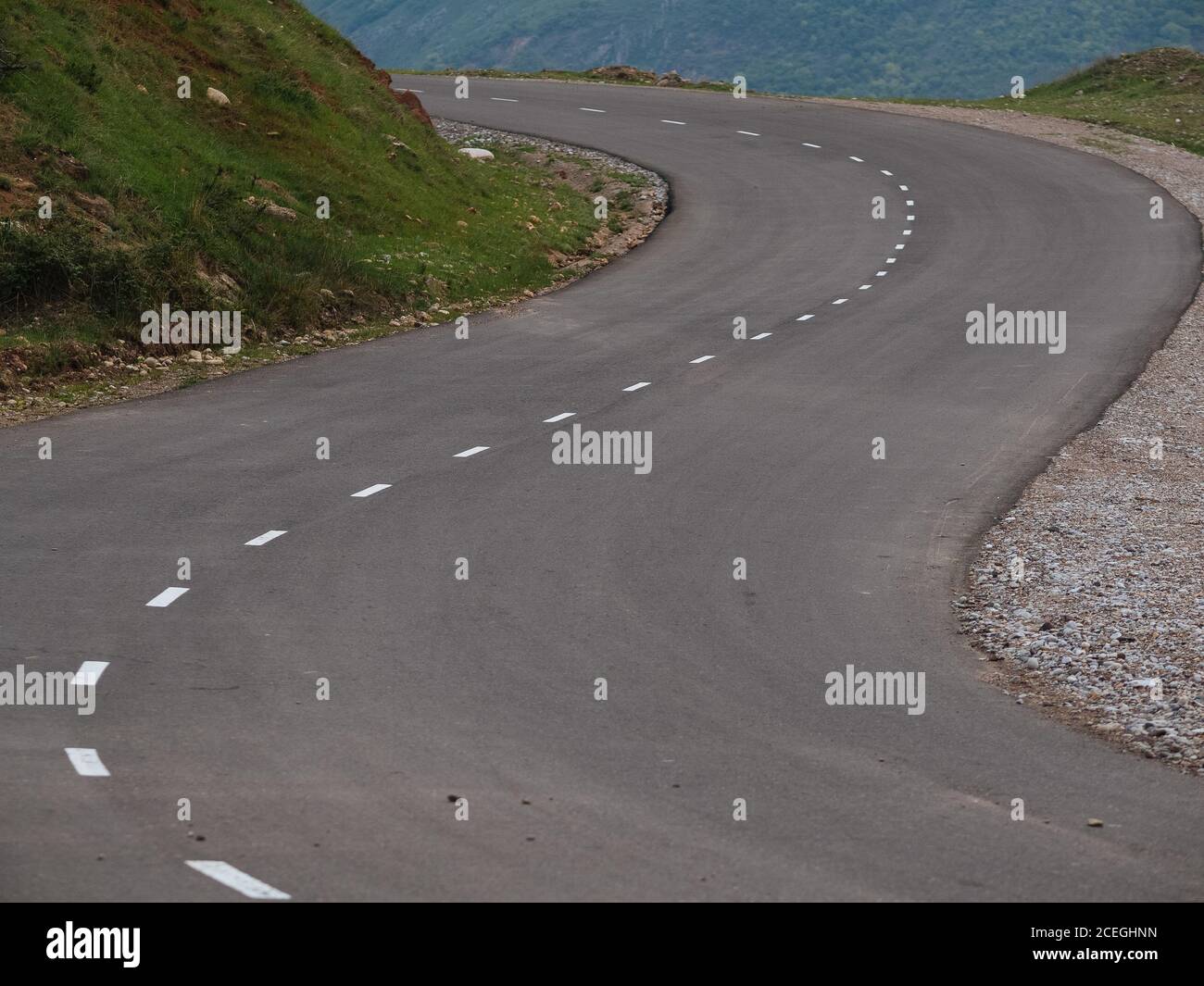 Asphalt Bürgersteig mit weißen Strich Linie Markierung geschwungen und läuft weg zwischen grünen Hügeln, Usbekistan Stockfoto