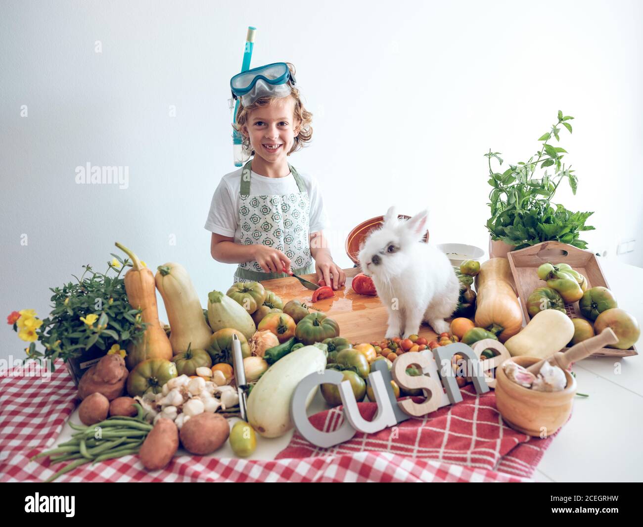 Kleiner Junge stehend und Kochen Gemüse am Tisch mit liebenswert Weißes Kaninchen Stockfoto