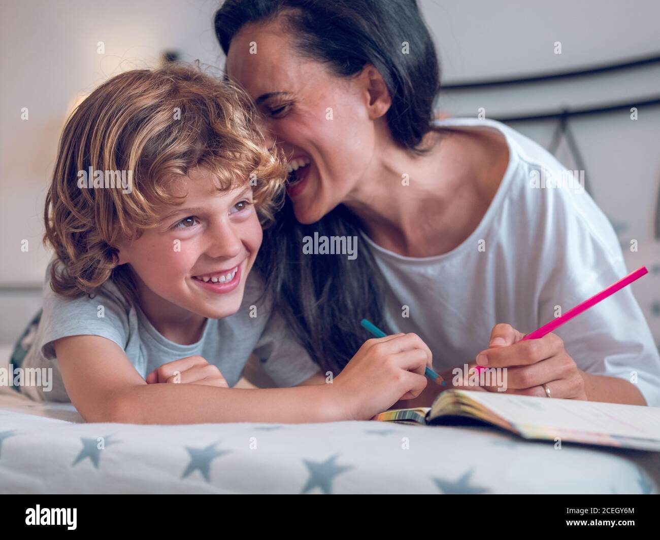 Schöne Frau und niedliches Kind liegen auf bequemen Bett und Färbung