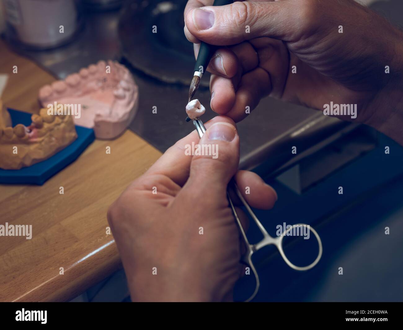 Crop Hände von Zahntechniker mit Werkzeugen zu schnitzen künstliche Zahn manuell Stockfoto