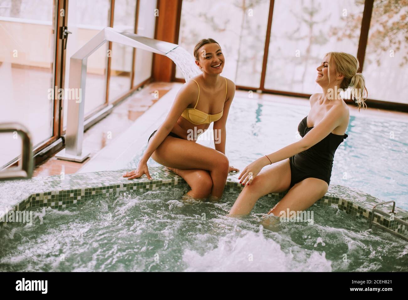 Hübsche junge Frauen sitzen und entspannen an der Whirlpool-Badewanne Stockfoto