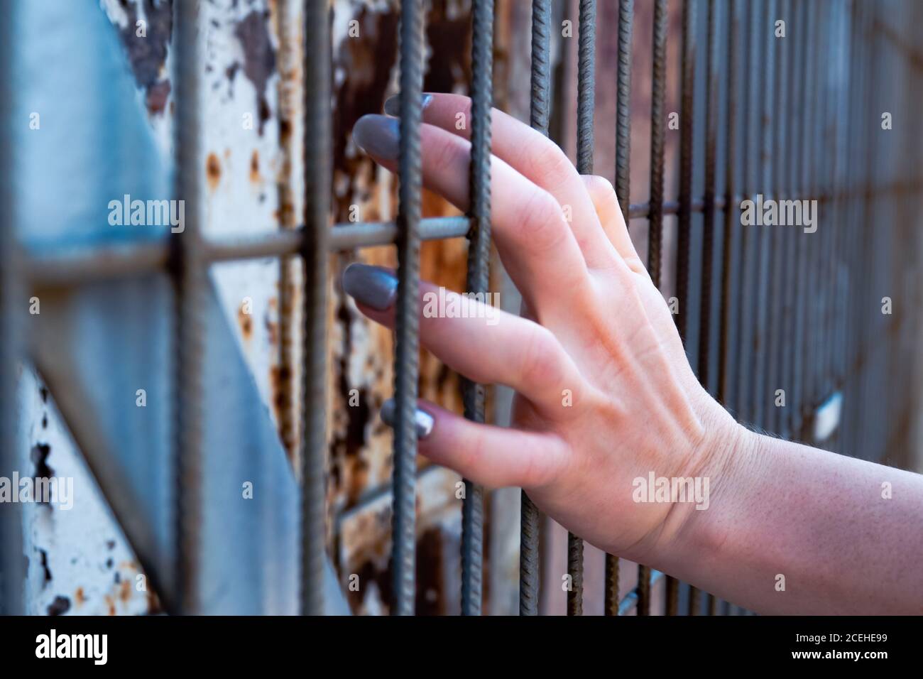 Schöne Mädchen Hand auf Eisenstangen beim Blick durch Drähte Stockfoto