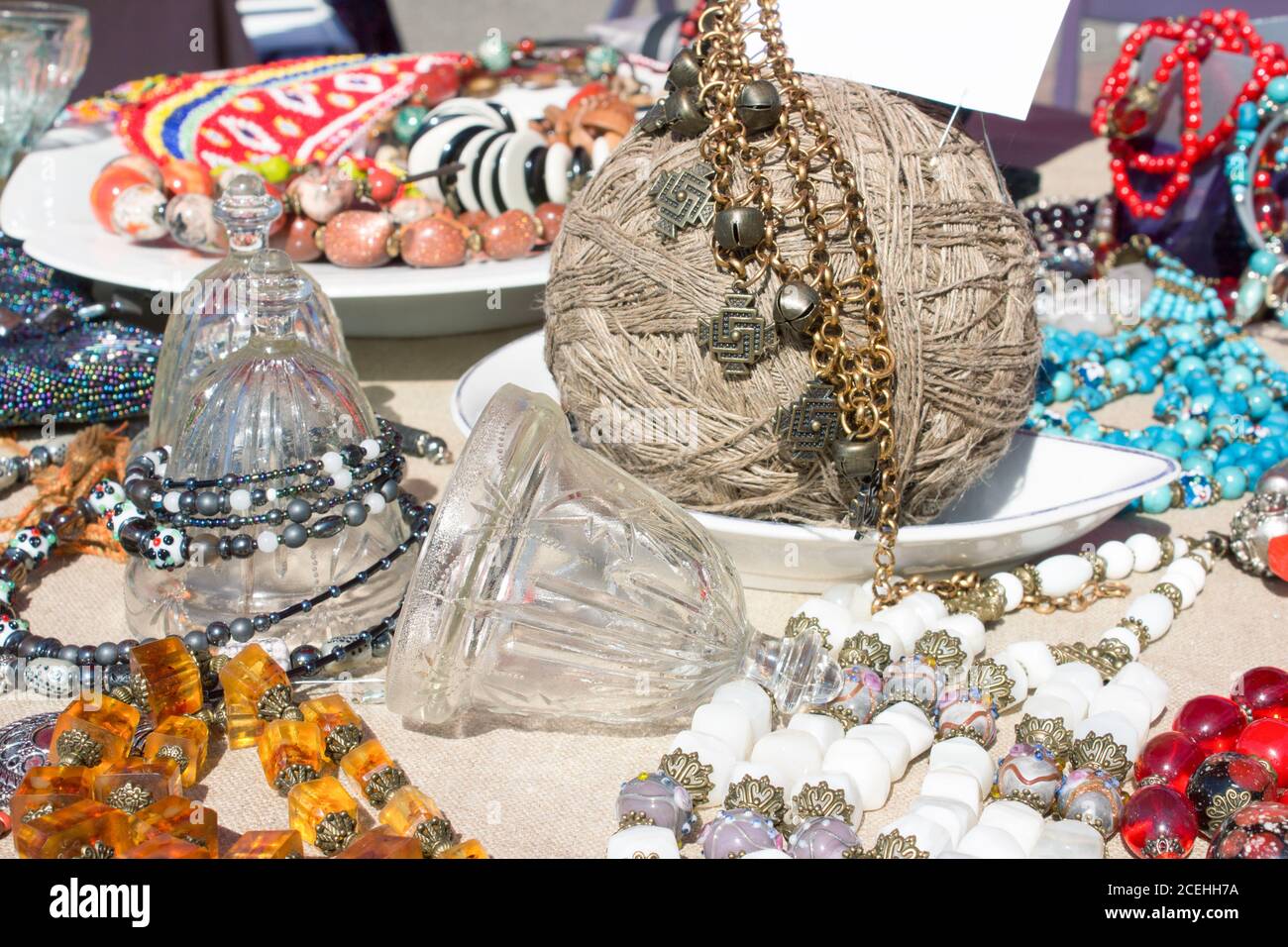 Verschiedene Antiquitäten auf Flohmarkt oder Festival - Sammlerstück Glas und Kristall Glocken, Vintage Amber und Metall Halskette und andere Vintage-Dinge Stockfoto