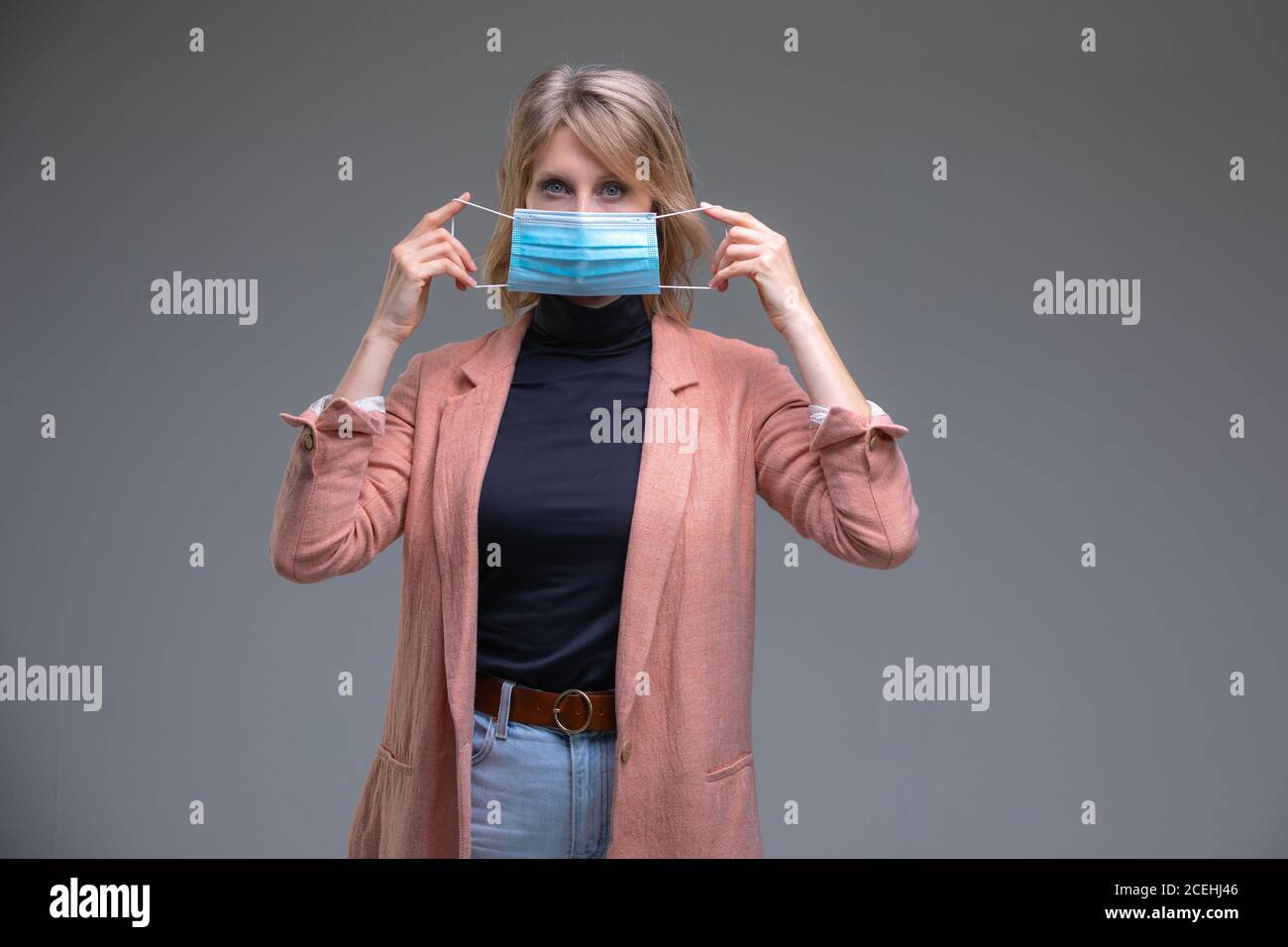 Blonde Frau halten ihre chirurgische Maske Stockfoto