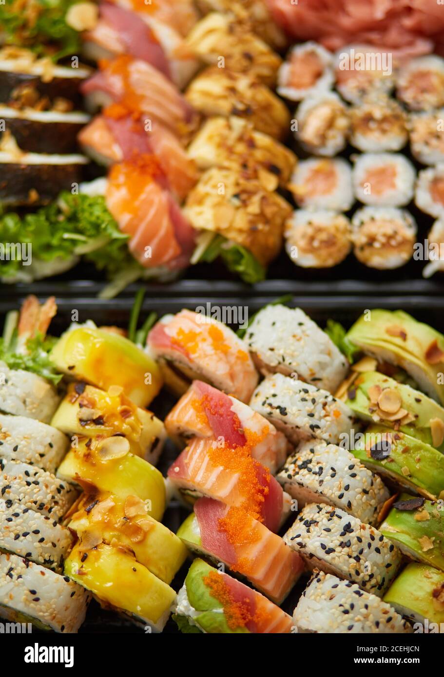 Nahaufnahme verschiedener Sushi-Sets in schwarzer Kunststoff-Lieferbox. Draufsicht Stockfoto