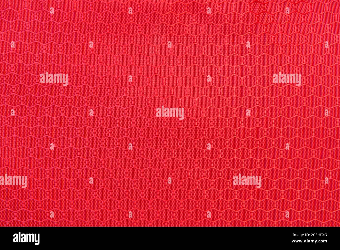 Rote Wabenhintergrund Textur. Textur Hintergrund aus Polyester-Gewebe. Muster aus Kunststoff-Webgewebe Stockfoto