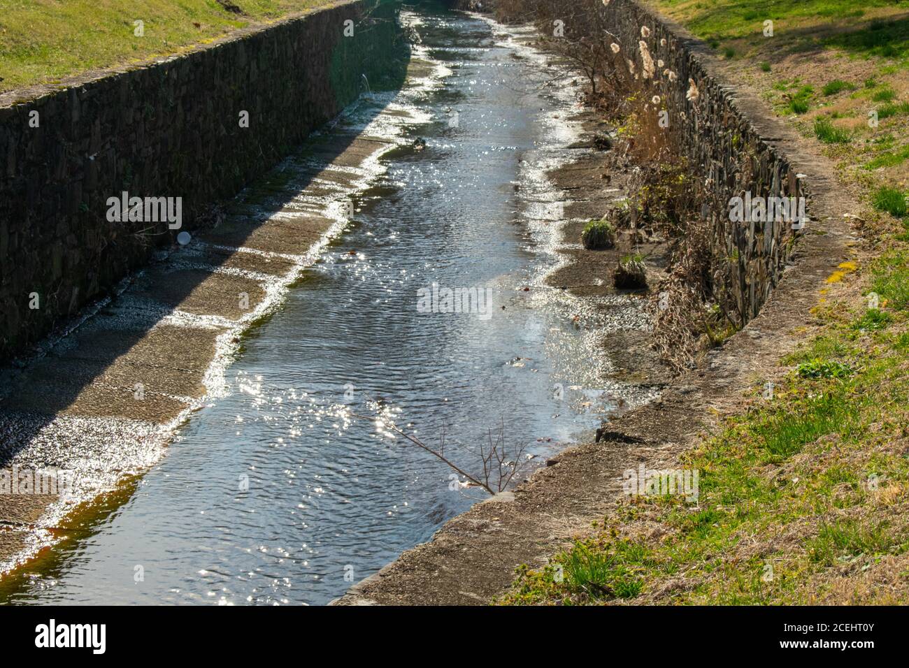 Ein von Menschen gemachter Kanal mit Kopfsteinpflasterwänden für Entwässerung und Überlauf Stockfoto