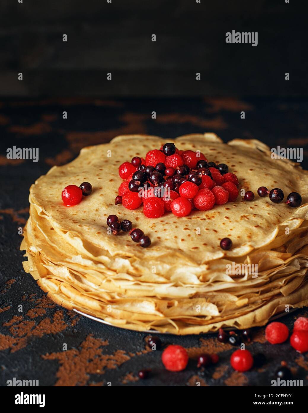 Russische Pfannkuchen mit Beeren vor dunklem Hintergrund. Pancake Week - das alte slawische Fest des Sehens aus dem Winter, von dem der Brauch Stockfoto