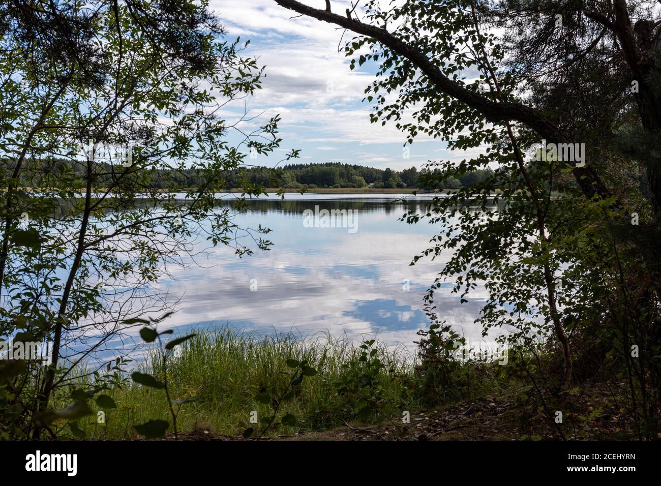 Himmel und Wolken spiegeln sich in einem ruhigen See. Blick auf die finnische Natur. Stockfoto