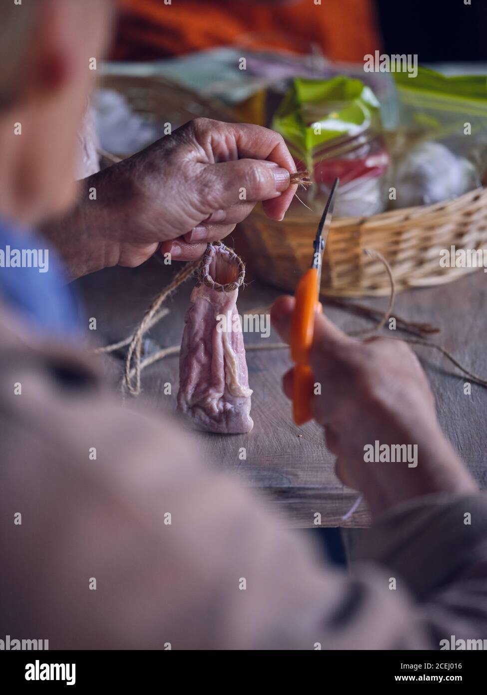 Unkenntlich ältere weibliche mit Schere Leinen Faden auf geschnitten Leere Tiernasen über dem Tisch Stockfoto