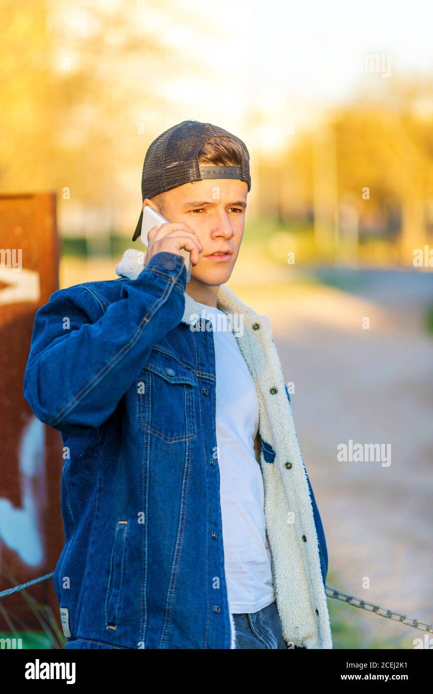 Porträt eines jungen Mannes im Freien trägt lässige Kleidung und Mit einem Smartphone Stockfoto