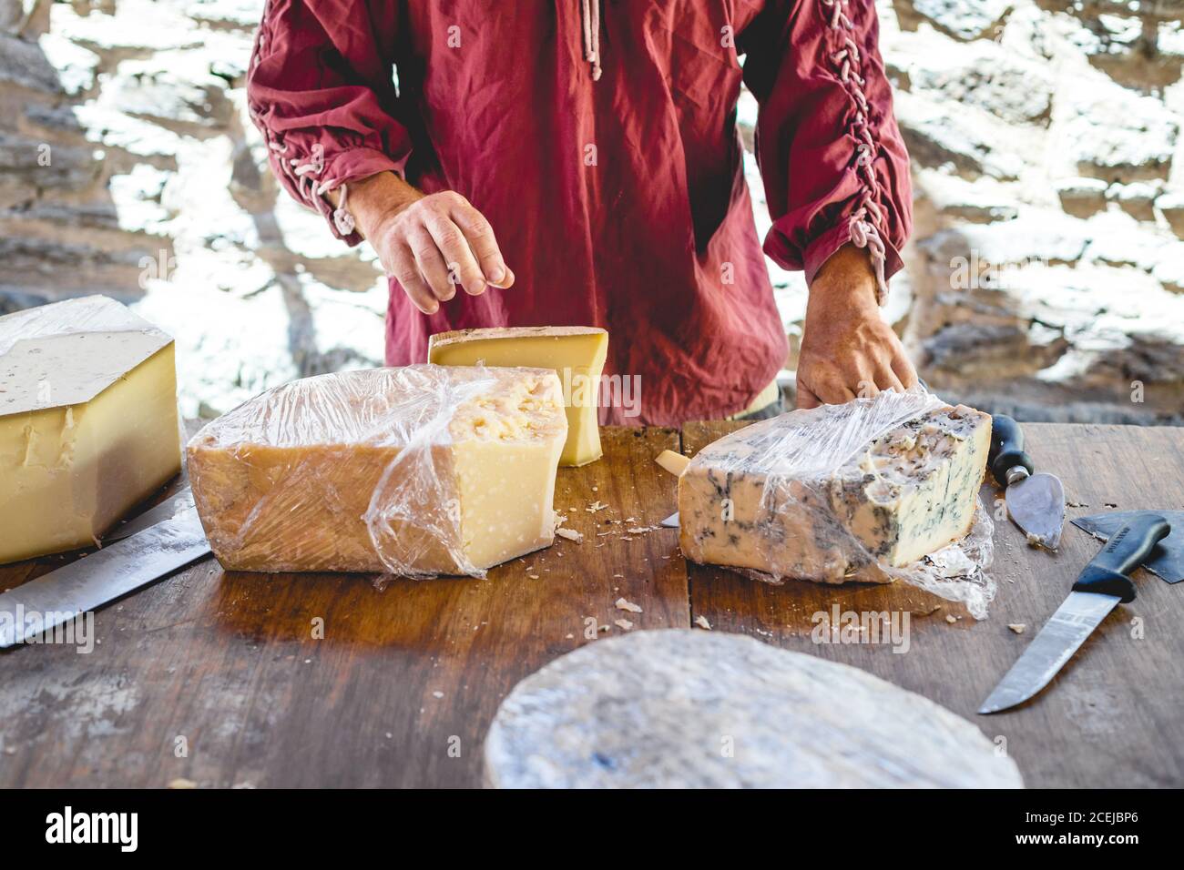 Crop Hand des Verkäufers geben dem Kunden ein Stück Käse auf Messer zum Verkosten Stockfoto