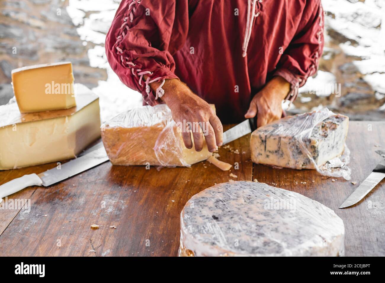 Crop Hand des Verkäufers geben dem Kunden ein Stück Käse auf Messer zum Verkosten Stockfoto