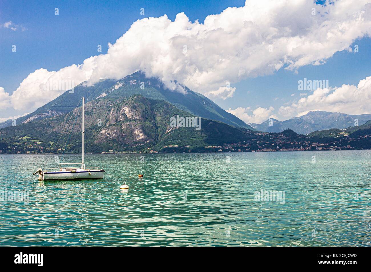 Blick auf Segelboot verankert im Hafen das Dorf Varenna am Comer See. Landschaftlich reizvolle Landschaft im Hintergrund alpen Berge, Bäume und Wasser. Mailand Stockfoto