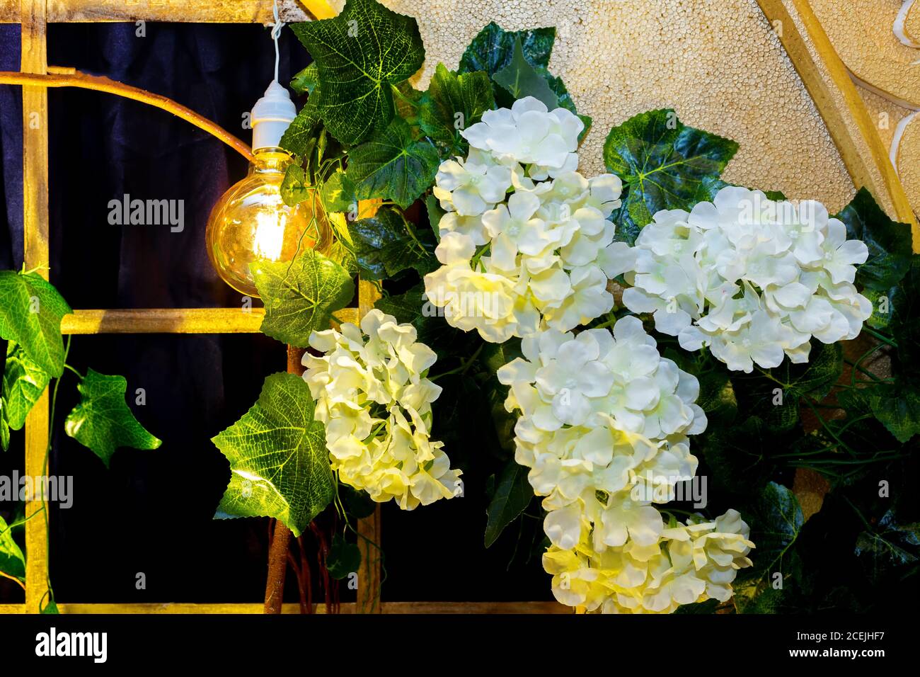 Bunte künstliche Blumen mit dekorativen antiken Edison Stil Glühbirnen hängen auf Hochzeit Bühnendekoration. Stockfoto