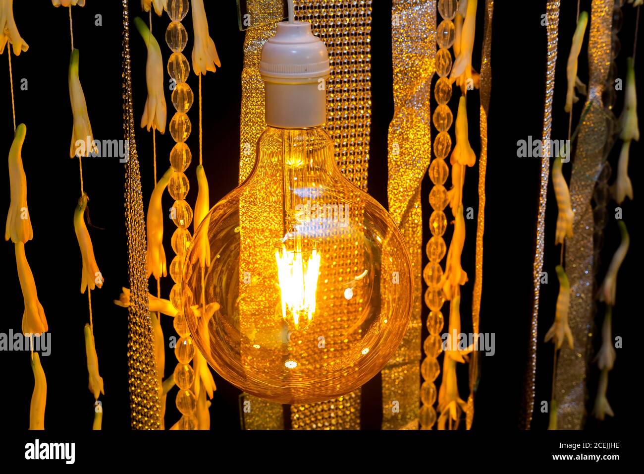 Bunte künstliche Blumen mit dekorativen antiken Edison Stil Glühbirnen hängen auf Hochzeit Bühnendekoration. Stockfoto