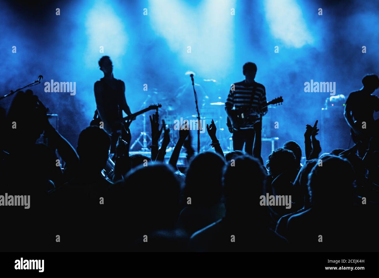 Beliebte Band spielt Musik unter blauem Licht auf der Bühne club für eine Gruppe von jubelnden Fans Stockfoto