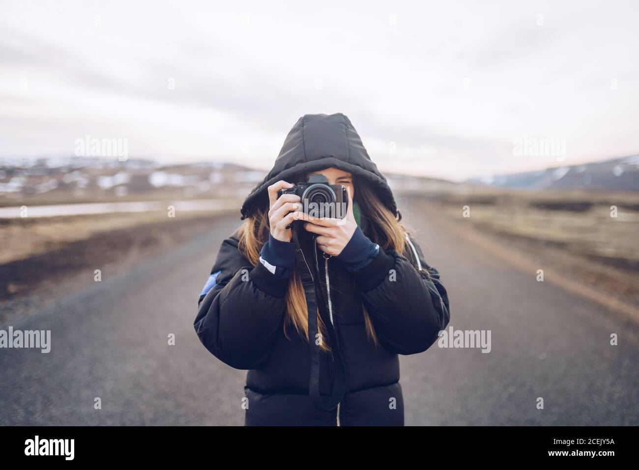 Junge Dame in Skijacke Blick durch die Kamera auf der Straße Zwischen wilden Ländern in Island Stockfoto