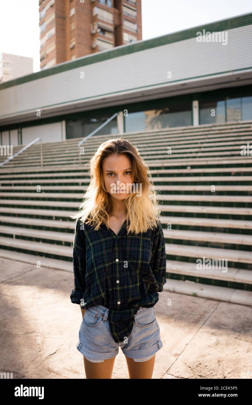 Schöne junge Frau in Shorts und Hemd in der Nähe von Treppen und Gebäude auf der Straße der Stadt Stockfoto