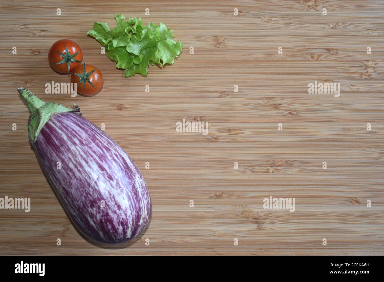 Frische ungekochte Graffiti Aubergine / Aubergine / Brinjal mit Tomaten und Salat, auf Holzschneidebrett. Kopieren Sie den Platz auf die rechte Seite. Stockfoto