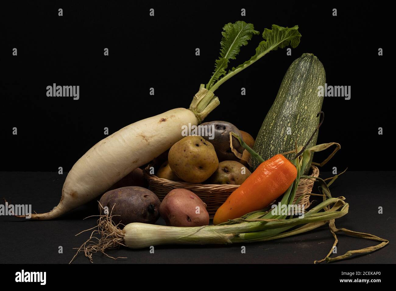 Stillleben von Gemüse in niedrigen Schlüssel. Verschiedene Arten von Gemüse im Studio erschossen. Kartoffeln, Rüben, Kürbis, Zwiebeln, Frühlingszwiebeln und Chili. Stockfoto