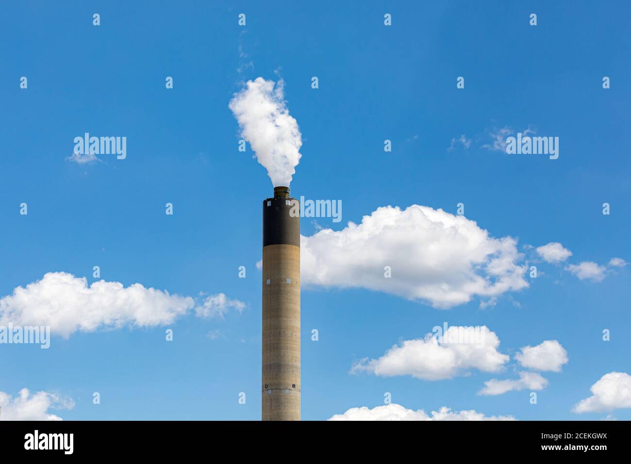 Schornstein eines Kohlekraftwerks mit weißem Rauch, der sich am blauen Himmel erhebt. Konzept der Luftverschmutzung durch fossile Brennstoffe, der globalen Erwärmung und des Klimawandels Stockfoto