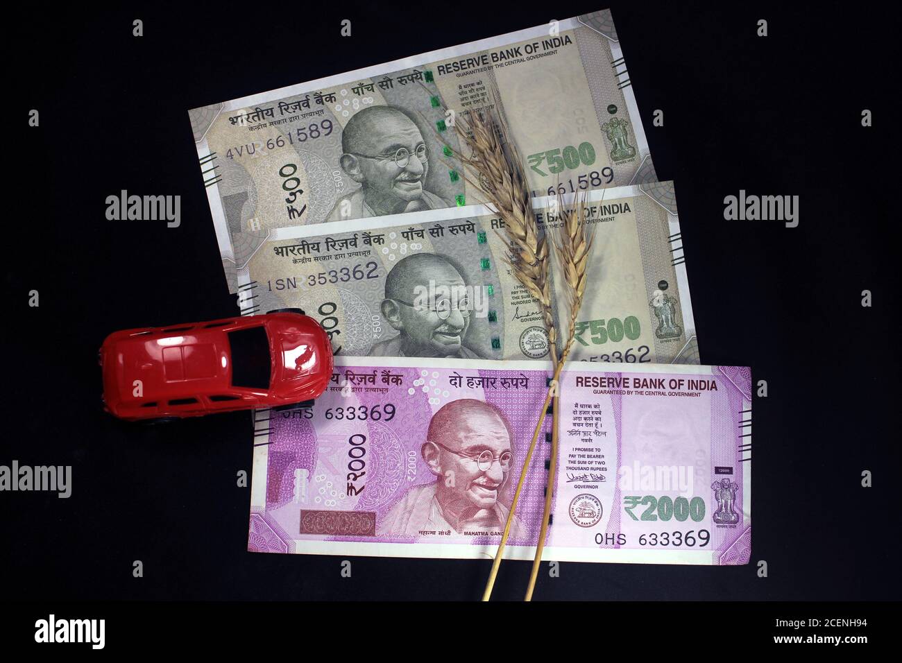 Neue indische Währungen. 500 und 2000 Rupien Noten mit Weizenkörnern und roten Farbe Spielzeugauto. Indische Währung auf schwarzem Hintergrund isoliert. Stockfoto