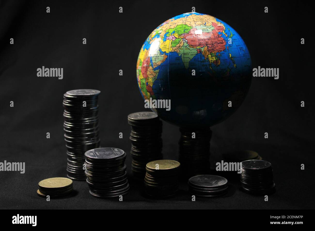 Vorratsstapel von 1, 2, 5, 10 Indische Rupie Metall Münze Währung mit Globus isoliert auf schwarzem Hintergrund. Finanz-, Wirtschafts-, Investitionskonzept. Stockfoto