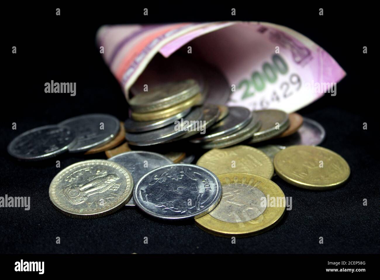 Neue indische Währung. 2000 Rupie-Note mit Münzen. Indische Währung auf schwarzem Hintergrund isoliert. Stockfoto