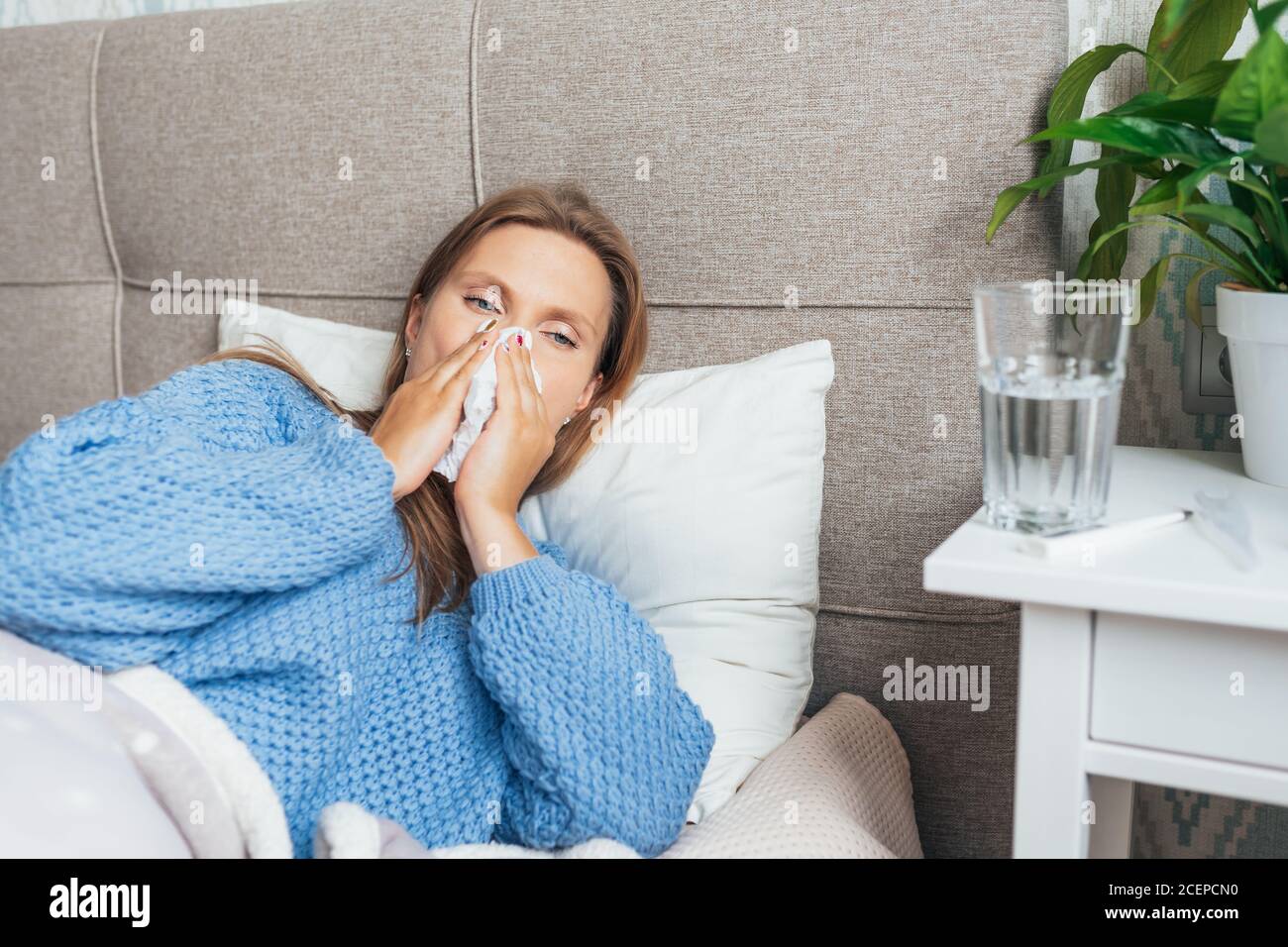 Junge Frau leidet zu Hause an Grippe. Frau bläst ihre Nase hält Gewebe Taschentuch, mit Symptomen einer chronischen Sinusitis, saisonale Allergie, Stockfoto